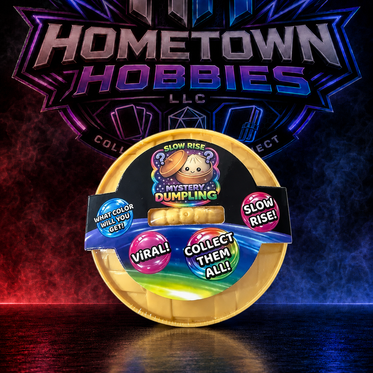 A collectible mystery dumpling product in a gold-colored oval container with a colorful label, displayed in front of a branded Hometown Hobbies LLC background with dramatic red and blue lighting.