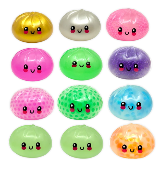 Twelve cute, round, dumpling-shaped stress relief toys arranged in a 3x4 grid on a solid white background. Each toy has a different color (gold, silver, pink, magenta, green, purple, blue, light green, orange) and a unique texture, either smooth or dotted with small beads.