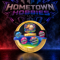 A collectible mystery dumpling product in a gold-colored oval container with a colorful label, displayed in front of a branded Hometown Hobbies LLC background with dramatic red and blue lighting.