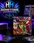 A boxed Pokémon MEGA Mini-Card Set box is displayed on a dark table with stacks of trading cards around it and a large Hometown Hobbies LLC logo in the background.