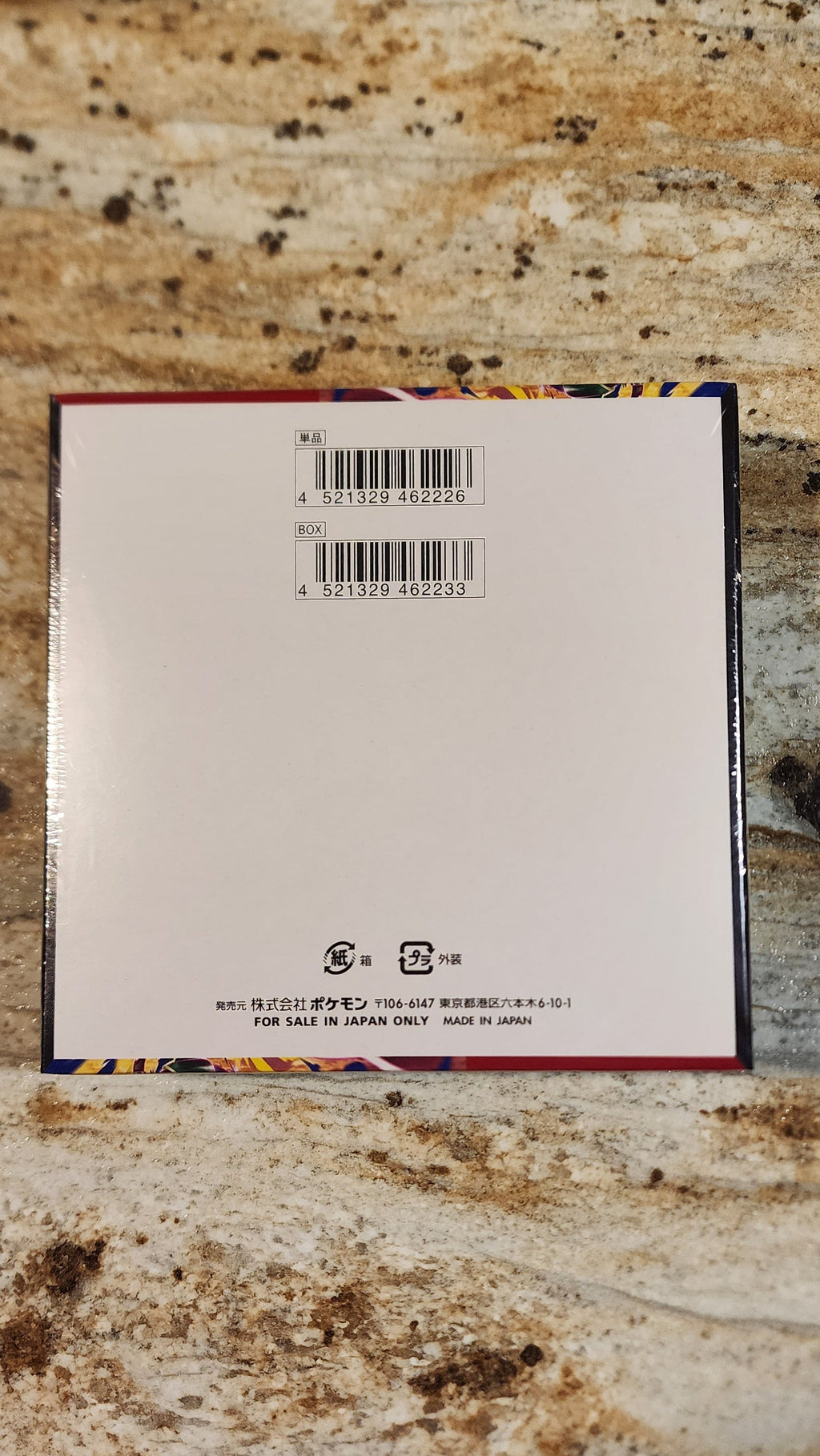 The back of a square product box with barcodes and small text, placed on a speckled granite countertop.